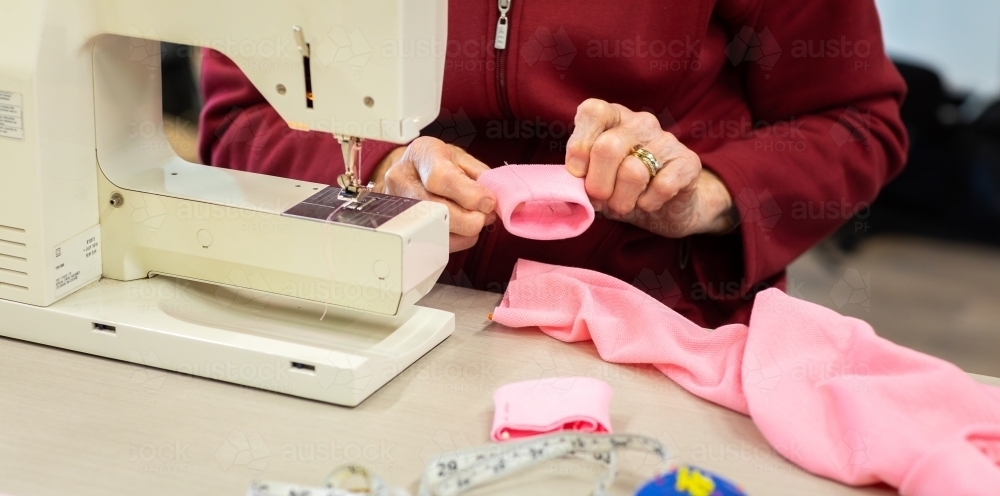 sewing machine with lady fitting cuff to garment - Australian Stock Image