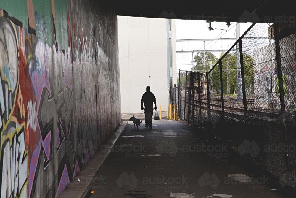 Shadow of a man and his dog walking beside a train track - Australian Stock Image