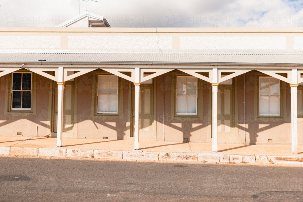Shadows cast along row of motel room doors along footpath in small country town - Australian Stock Image