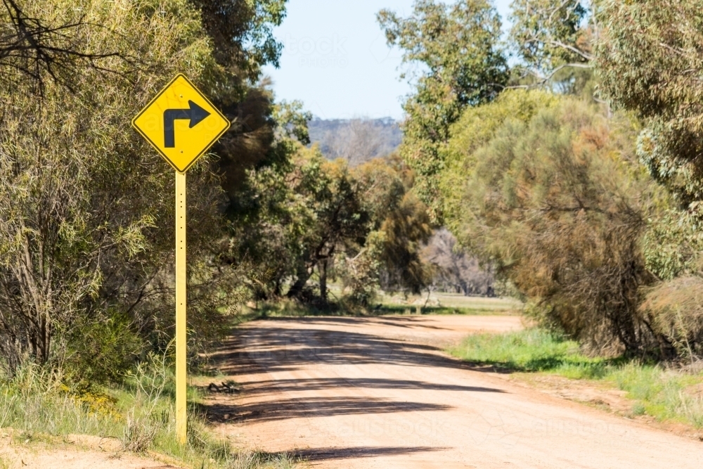 Sharp bend sign on unsealed country road - Australian Stock Image