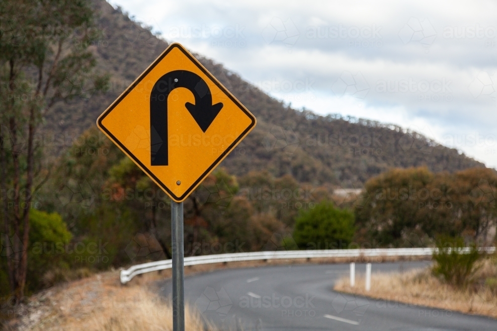 Sharp bend, turn in road sign on mountain road - Australian Stock Image