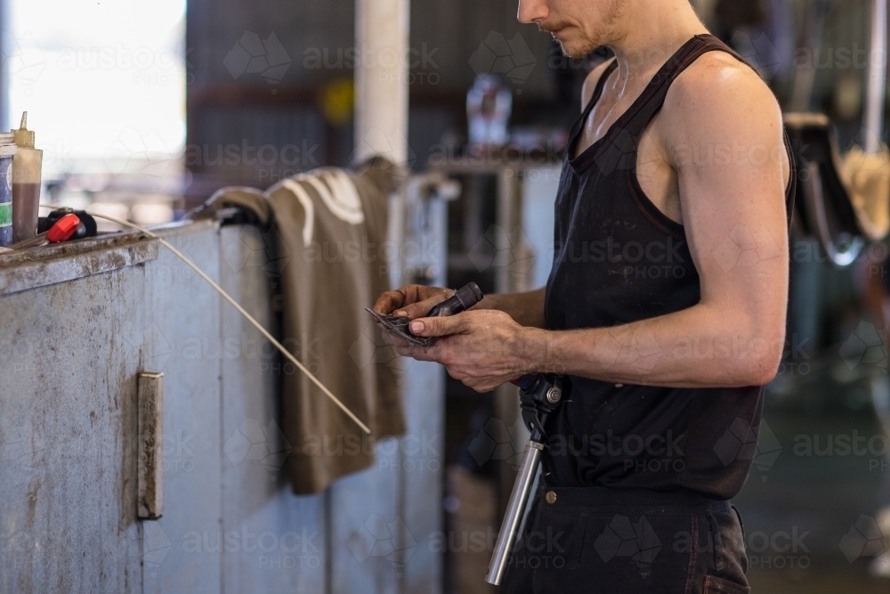 shearer holding handpiece on shearing board - Australian Stock Image