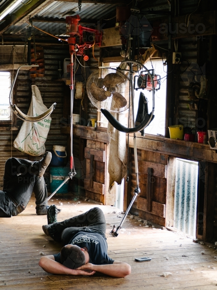Shearers resting on shed floor at smoko time - Australian Stock Image