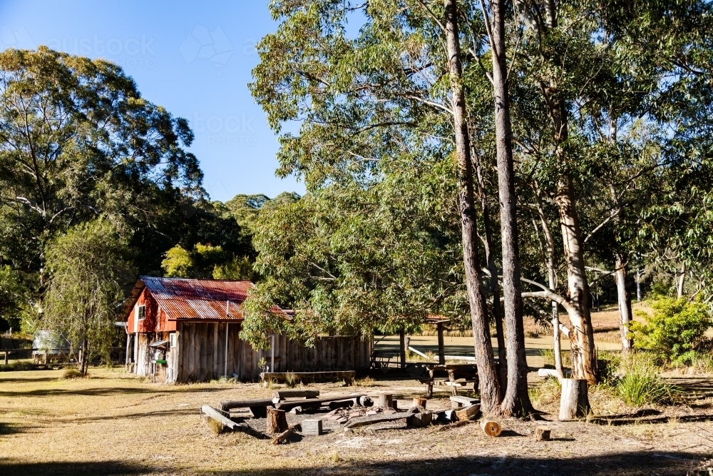 Shed and picnic area at campsite with campfire and seats - Australian Stock Image