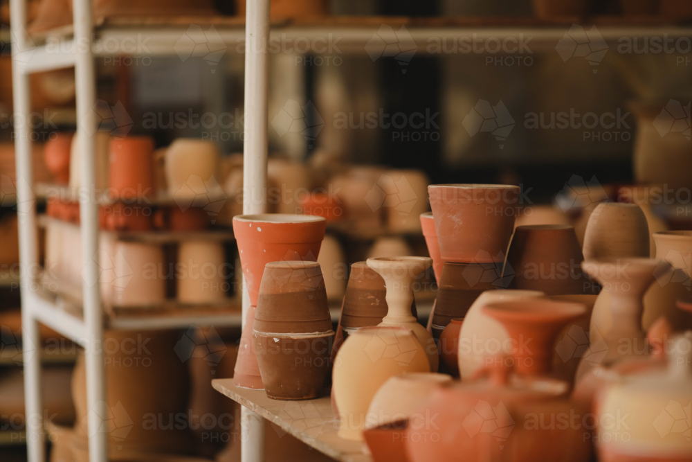 Shelves of clay pots and vases in studio, showcasing earthy tones and handcrafted textures - Australian Stock Image