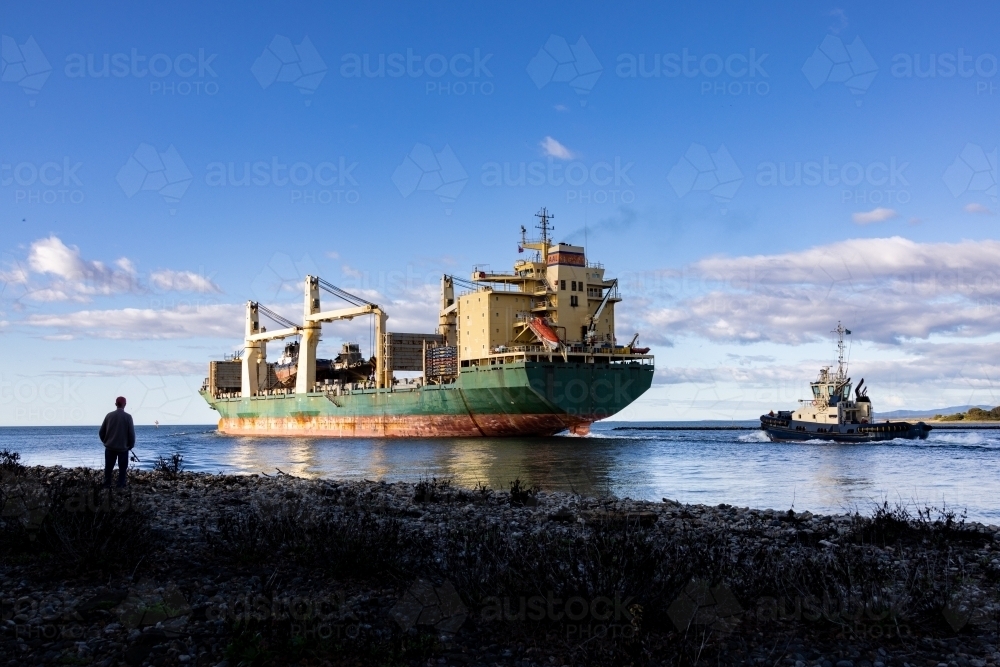 Ship leaving port with scrapped tug boats on board - Australian Stock Image