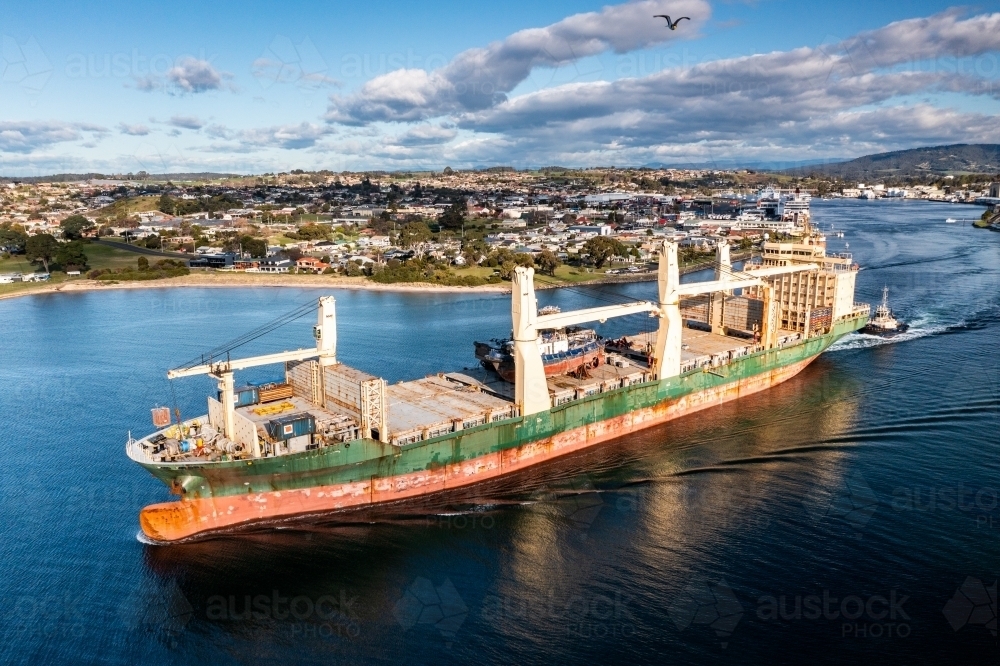 Ship leaving port with scrapped tugboats on board - Australian Stock Image