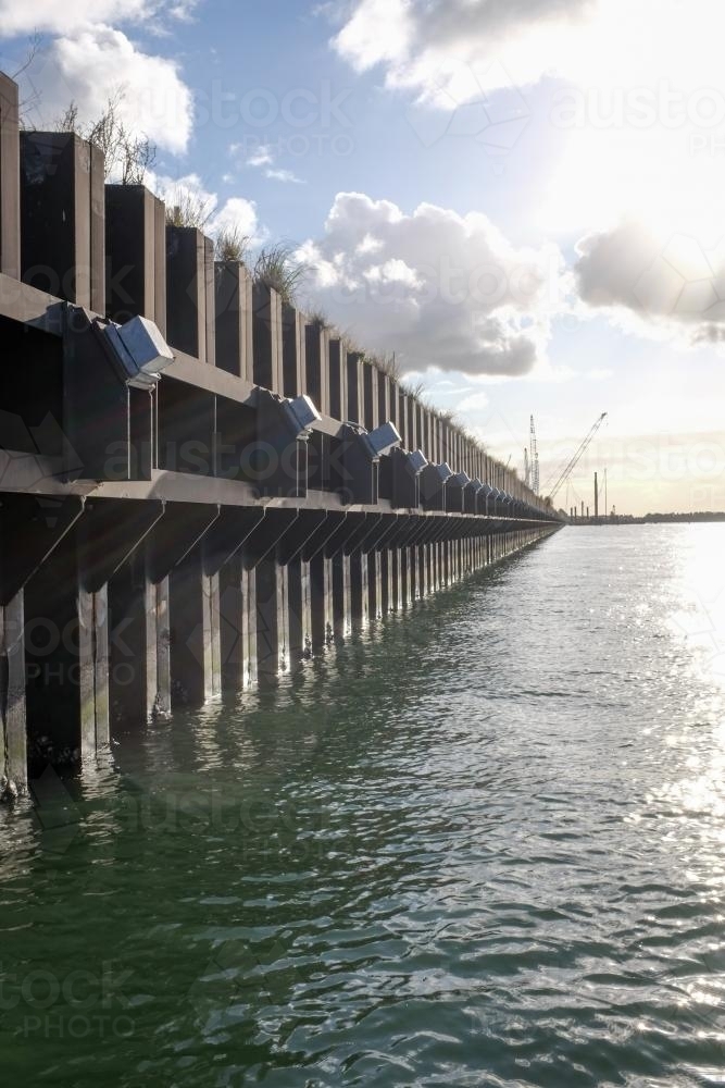 ship loading dock and cranes with sun shining through clouds - Australian Stock Image