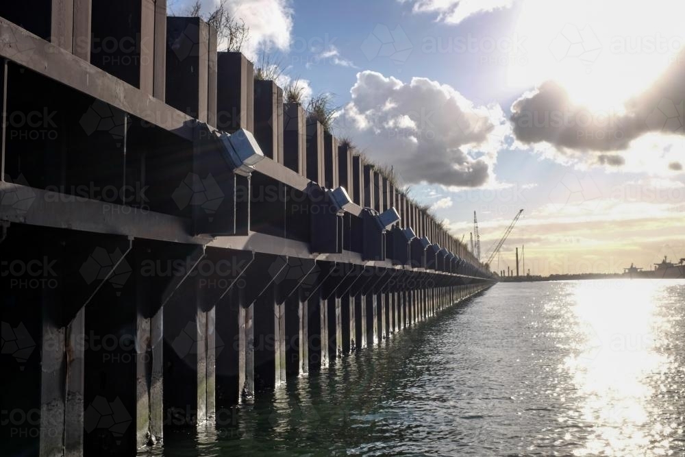 ship loading dock and cranes with sun shining through clouds - Australian Stock Image