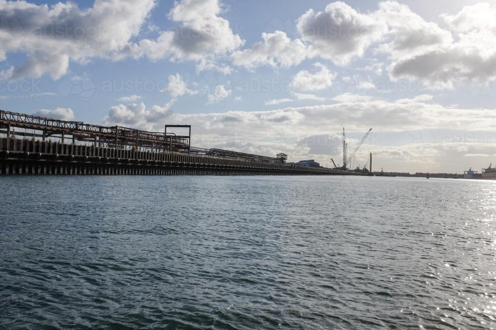ship loading dock and cranes with sun shining through clouds - Australian Stock Image
