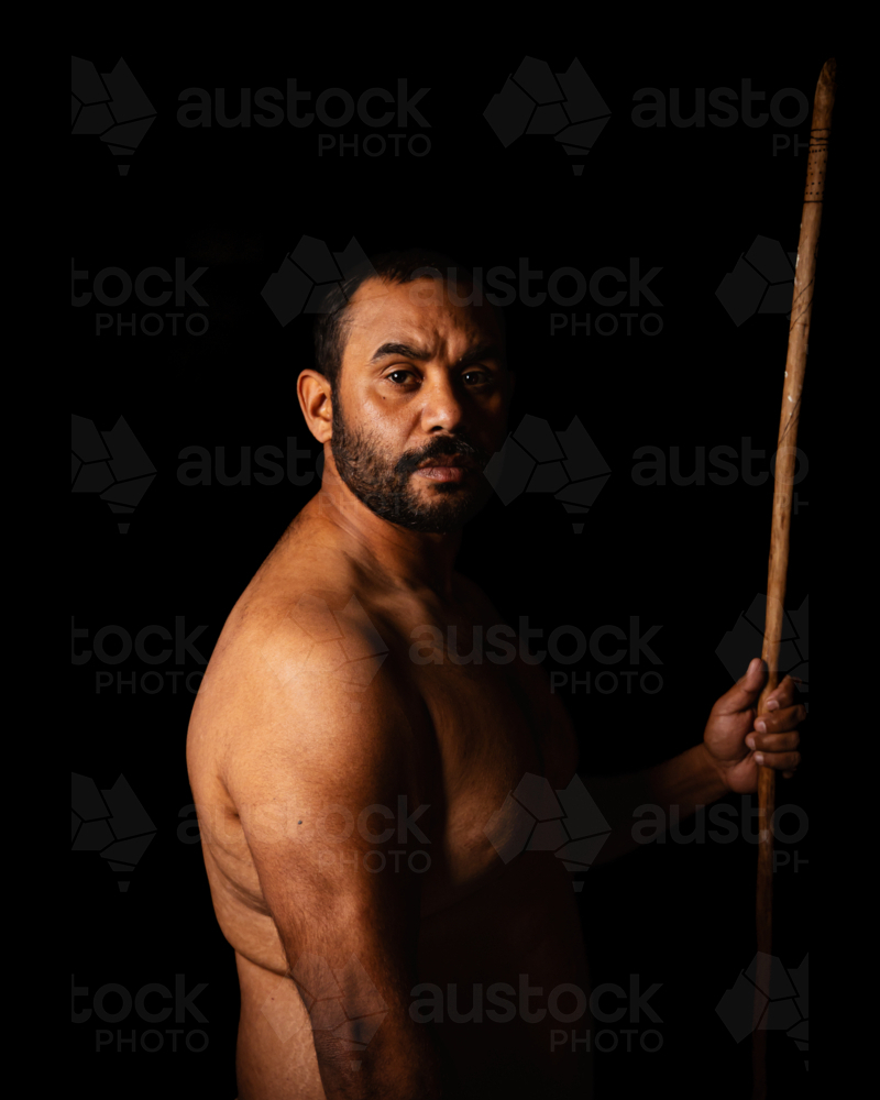 Shirtless aboriginal man holding a wooden spear - Australian Stock Image