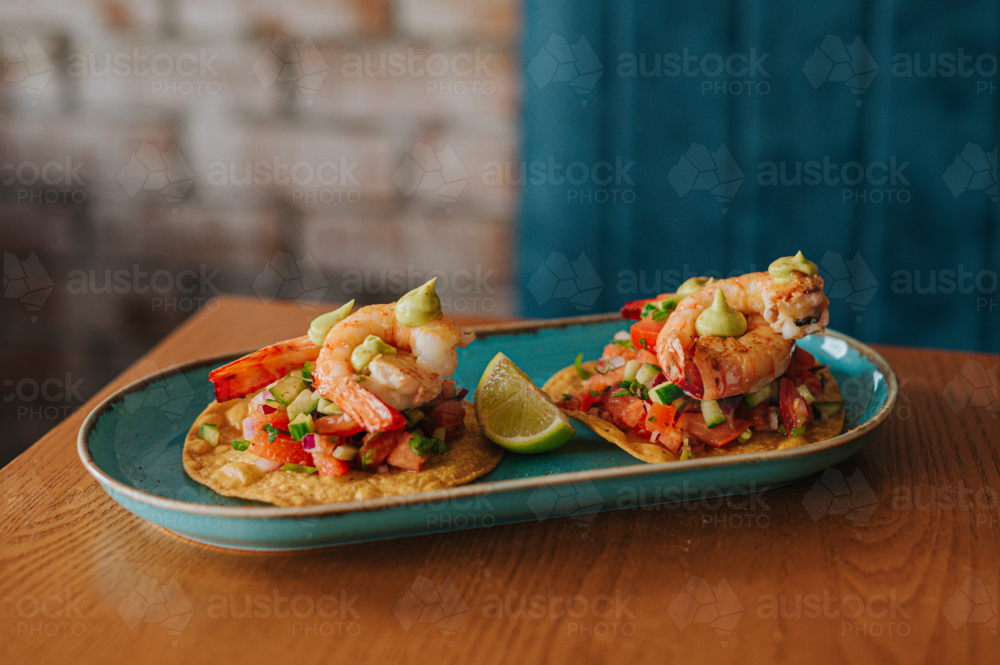Shrimp Tacos Served on a Blue Plate With Lime Garnish in a Cosy Restaurant Setting - Australian Stock Image