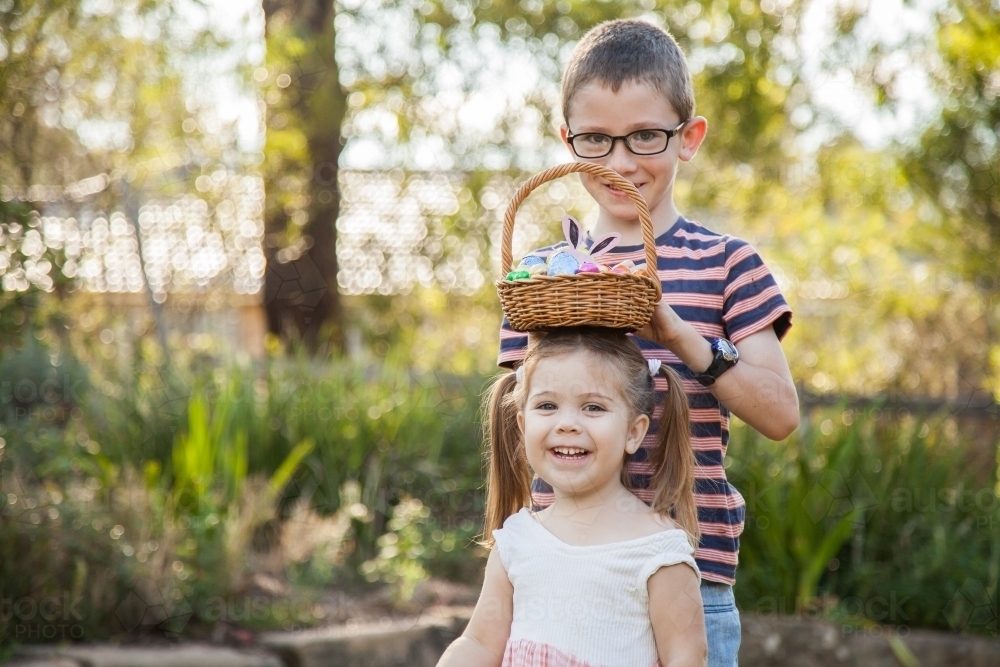 Siblings being silly with Easter egg basket in garden - Australian Stock Image