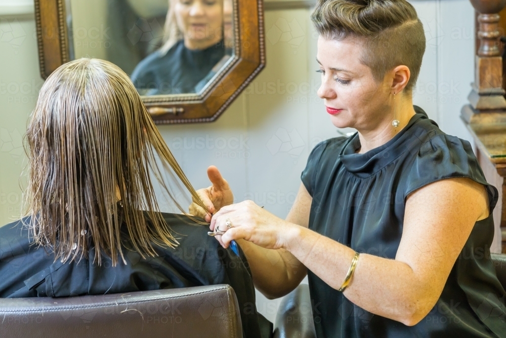 Side on view of a hairdresser cutting a ladies hair - Australian Stock Image