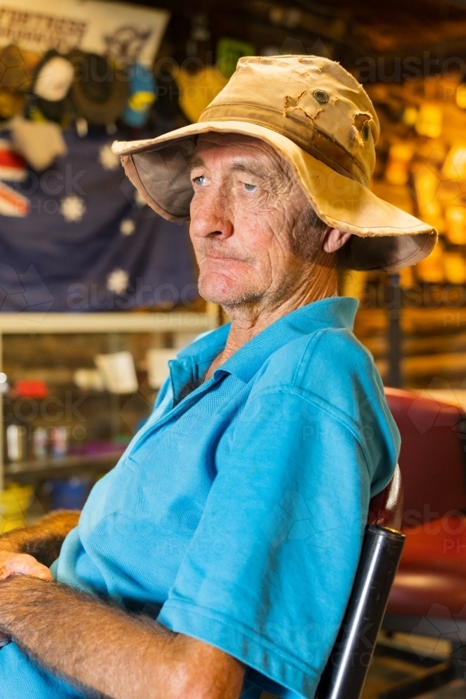 Side on view of an elderly man sitting in an outback, sitting and thinking - Australian Stock Image