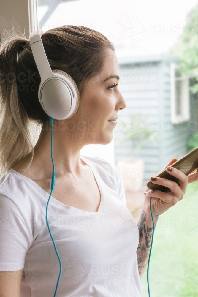 Side profile of a girl listening to music on a smartphone - Australian Stock Image