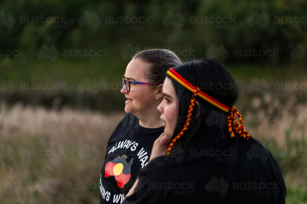 Side profile of aboriginal Australian mother and daughter outside in dim light at dusk - Australian Stock Image