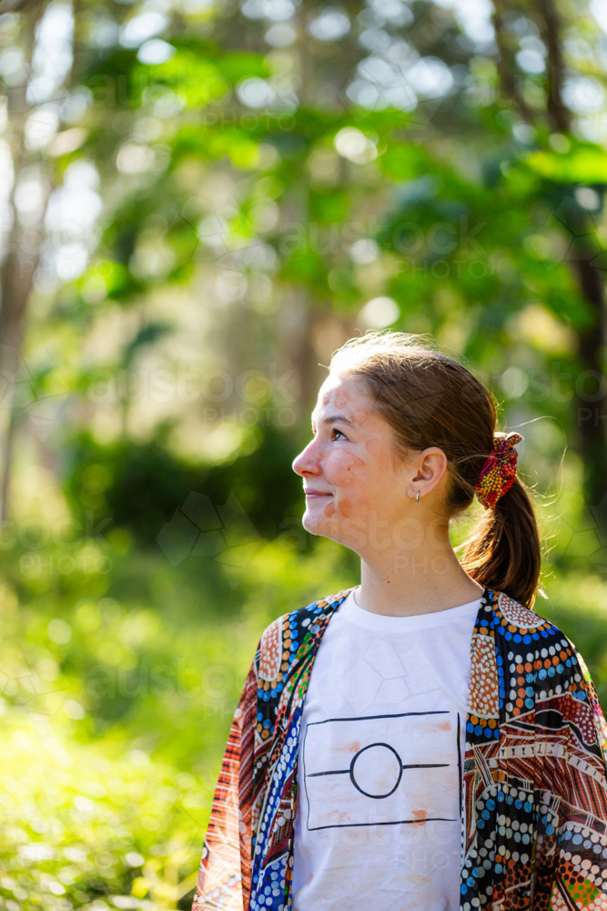 Side profile of aboriginal girl looking upwards in green bushland - Australian Stock Image