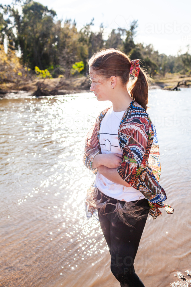 Side profile of aboriginal girl on sunny morning standing by river - Australian Stock Image