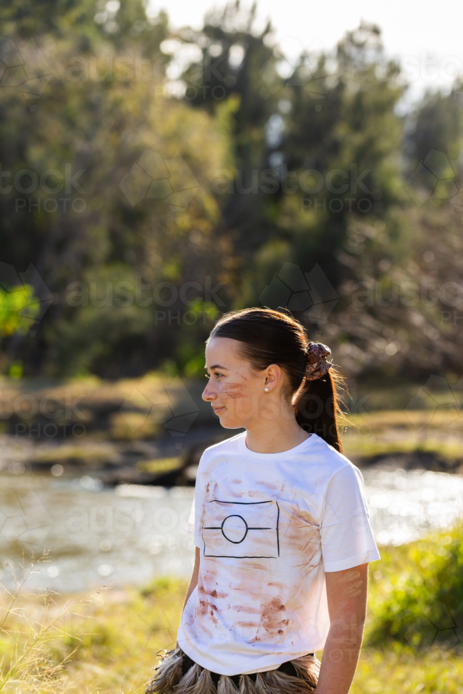 Side profile of teen aboriginal kid outside by a river - Australian Stock Image