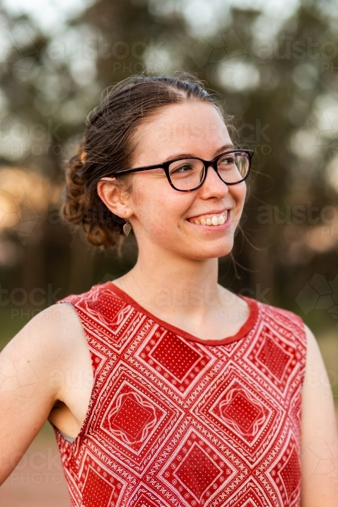 Side profile of young lady with glasses and messy bun outisde - Australian Stock Image