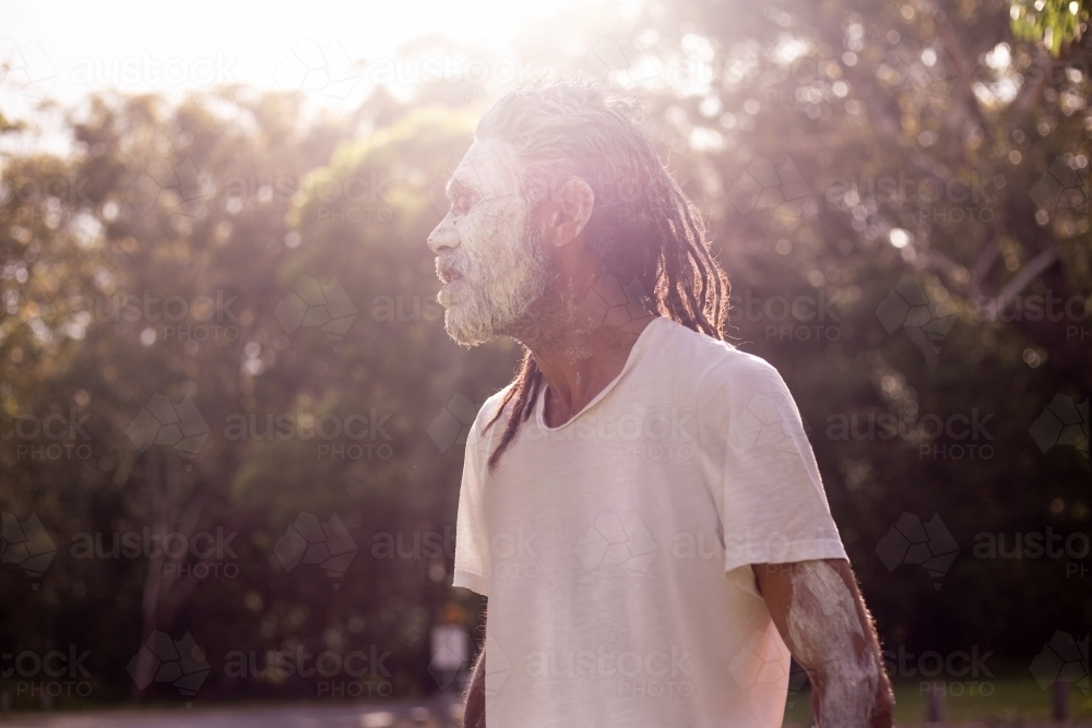 Side profile portrait of aboriginal man with sun flare - Australian Stock Image