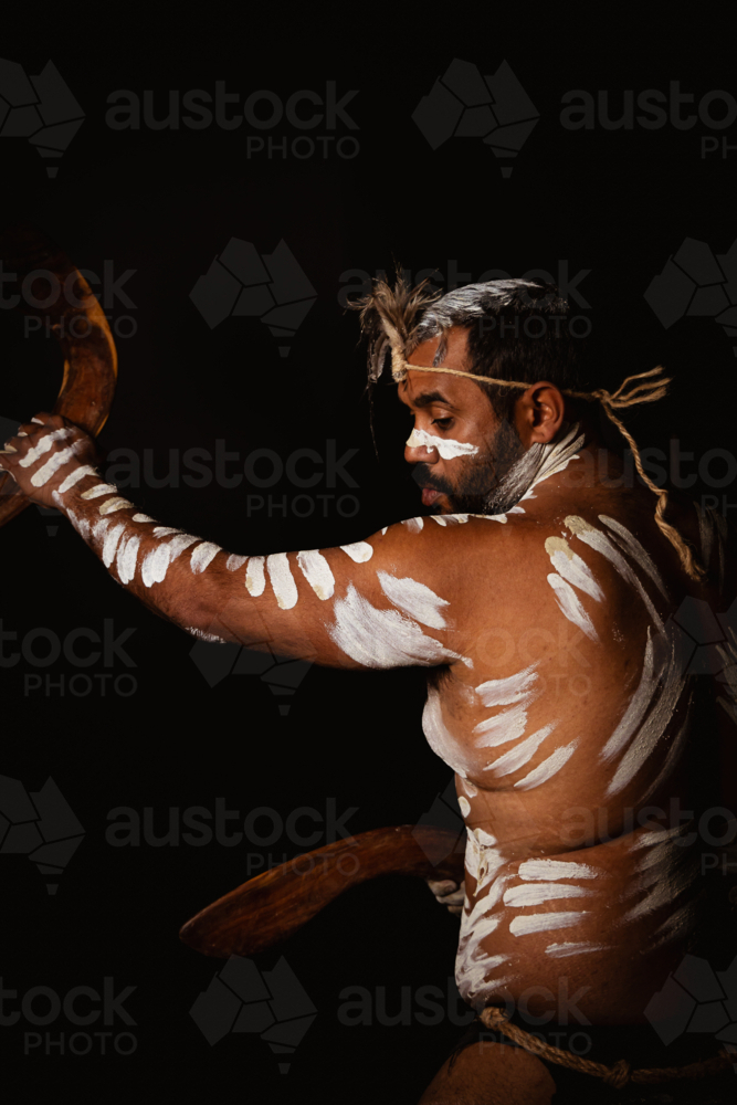 Side shot of Aboriginal male holding boomerangs - Australian Stock Image
