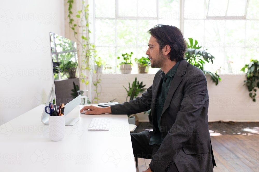 Side view of a man working on a computer in a creative studio - Australian Stock Image