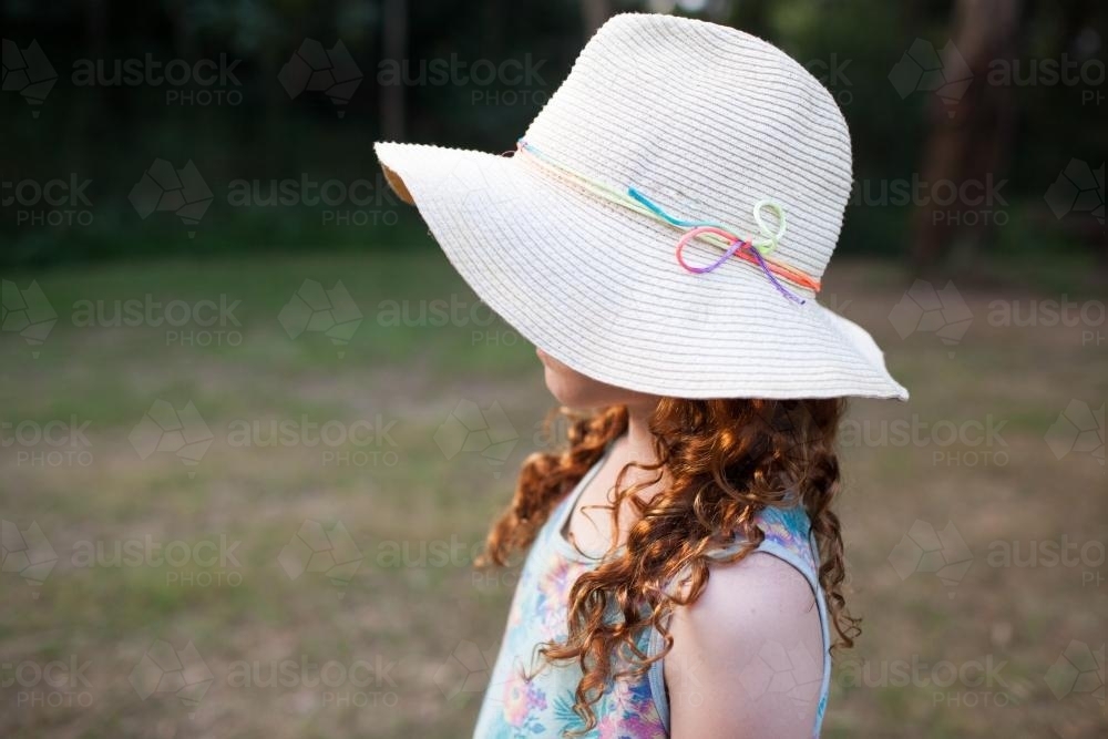 Side view of a young girl wearing a floppy hat - Australian Stock Image