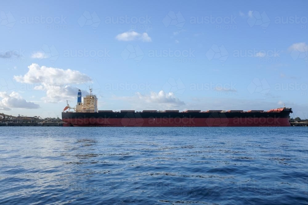 Side view of cargo ship docked in harbour - Australian Stock Image