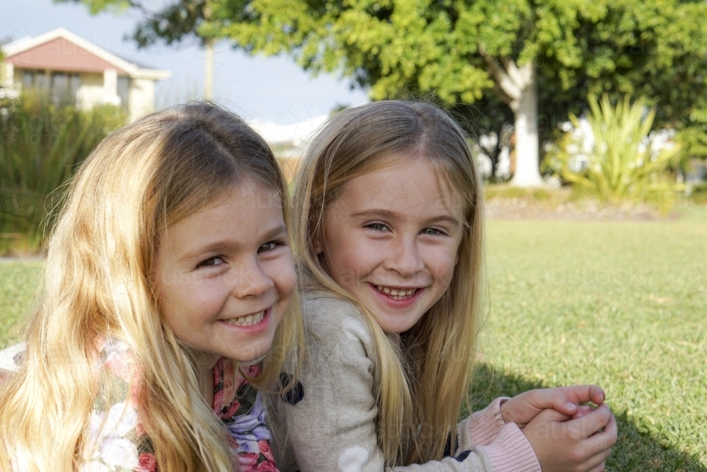 Side view of two young girls laying on grass - Australian Stock Image
