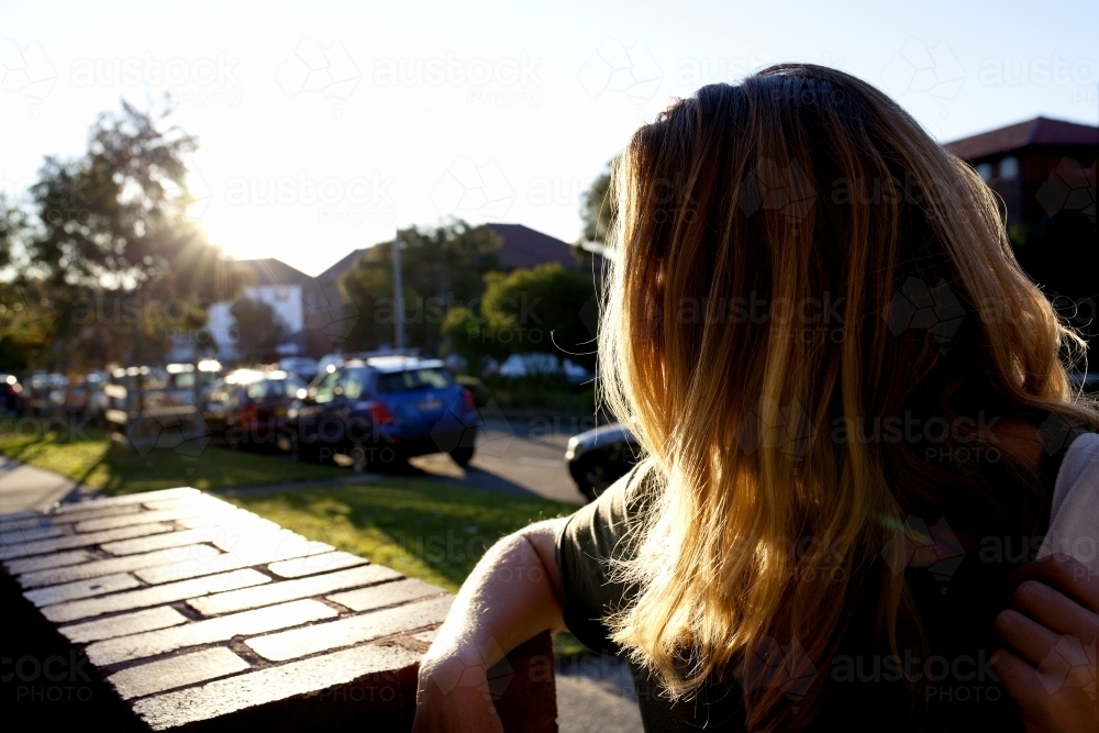Side view of woman leaning on brick wall - Australian Stock Image