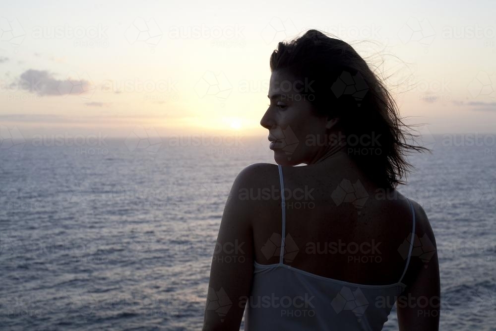 Side view of woman with ocean sunset - Australian Stock Image