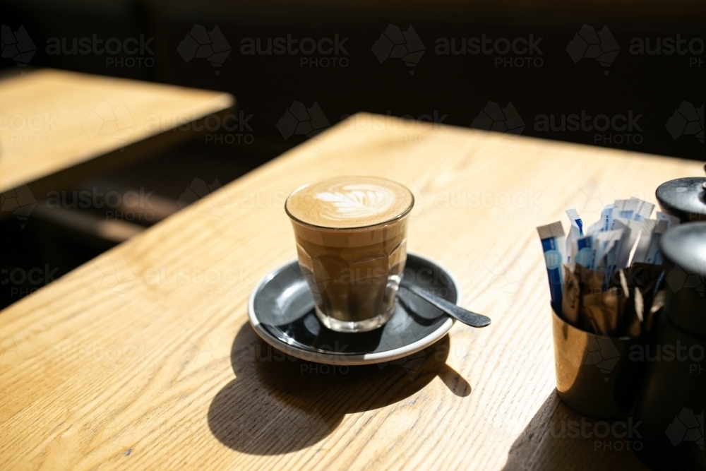 Side view shot of coffee art in a cup and a teaspoon in a table - Australian Stock Image