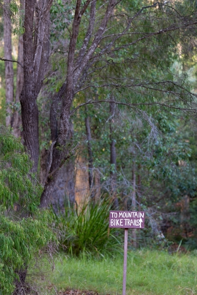 sign on edge of forest indicating direction to mountain bike trails - Australian Stock Image