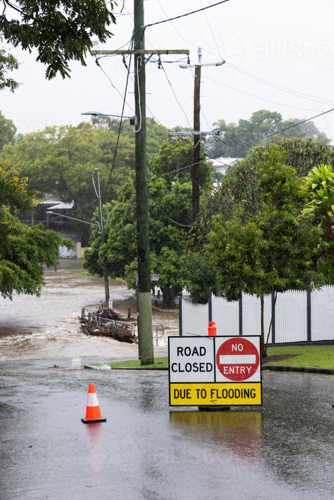 Signage across a flooded suburban road to stop traffic proceeding during a major rain event - Australian Stock Image