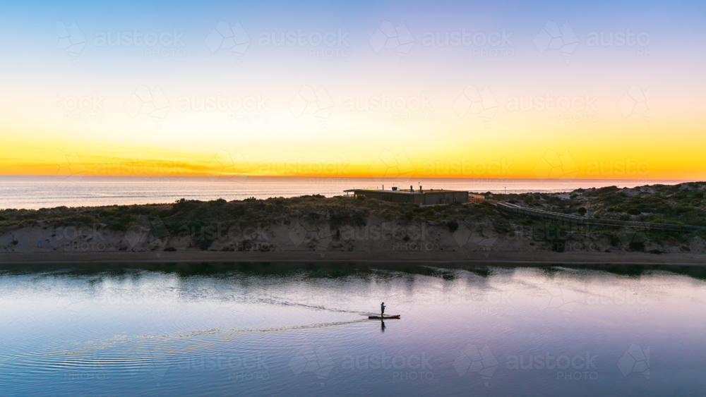 Silhouette of a man paddle boarding along the Onkaparinga River at dusk in South Port - Australian Stock Image