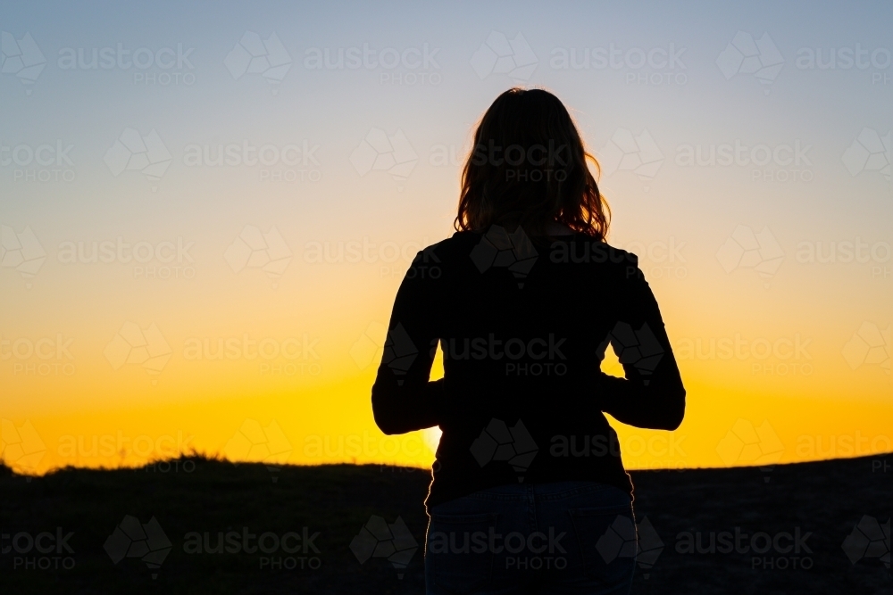 Silhouette of a person against a golden sunset - Australian Stock Image