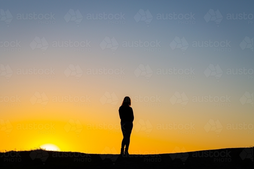 Silhouette of a person against a golden sunset - Australian Stock Image