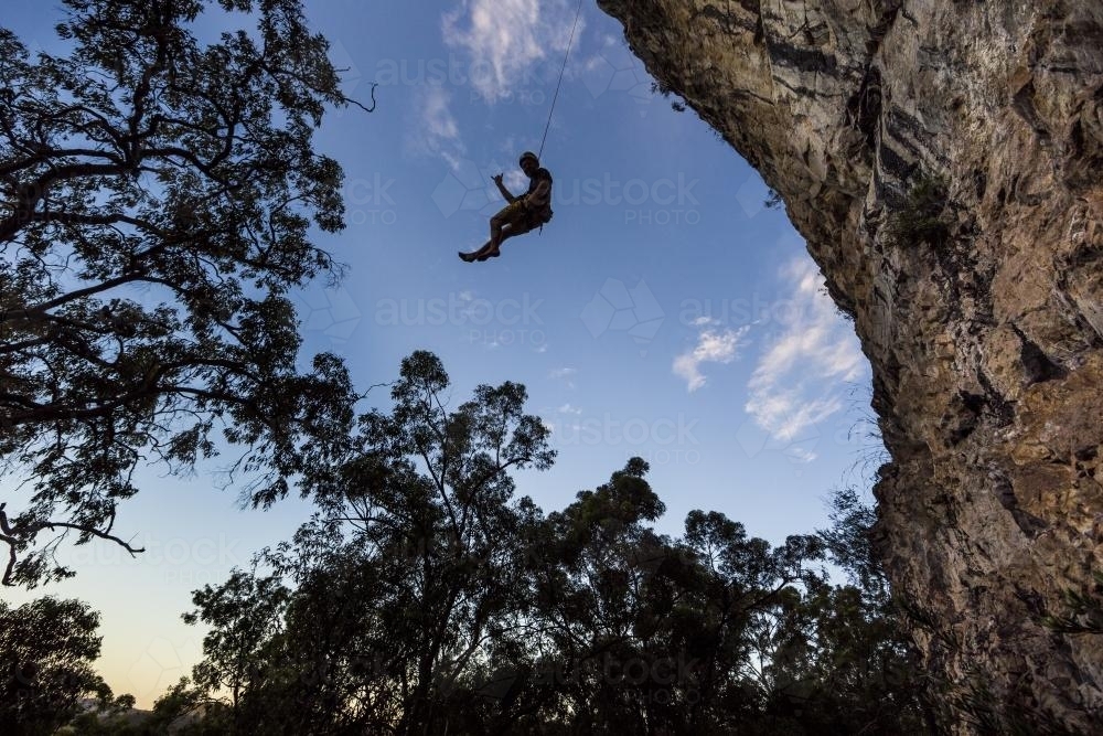 Silhouette of a rock climber being lowered on a rope - Australian Stock Image