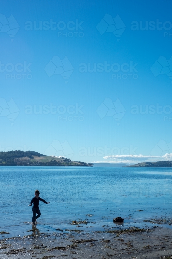 Silhouette of by playing in shallows at beach - Australian Stock Image