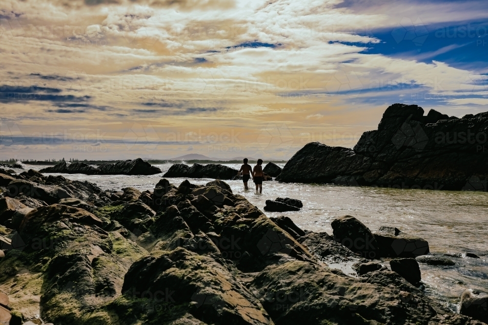Silhouette of children swimming at The Tanks tourist attraction natural rock pool - Australian Stock Image