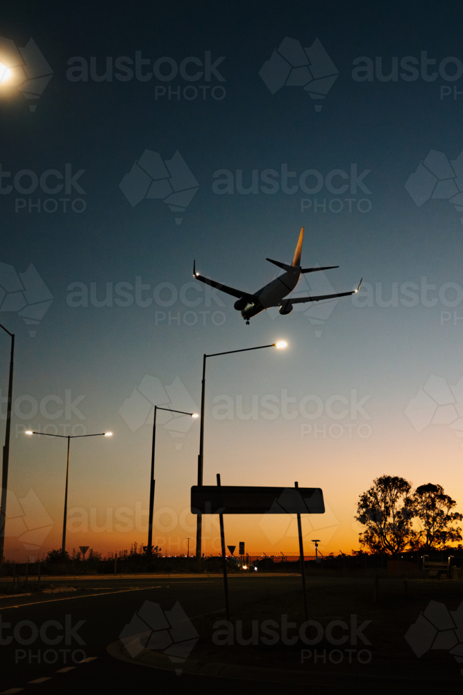 Silhouette of commercial airplane flying in the sky at sunset - Australian Stock Image