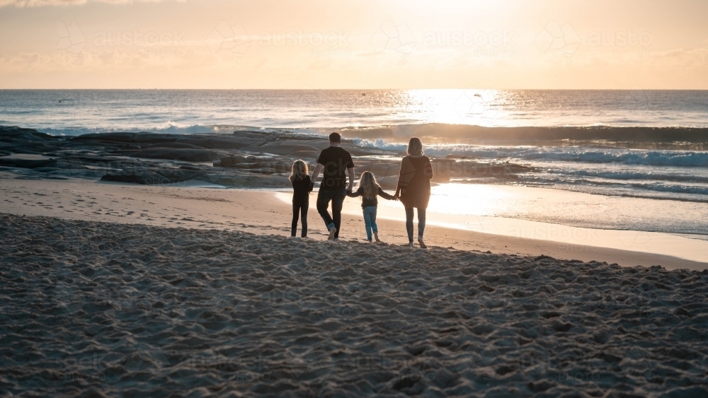 Silhouette of family walking into sunrise - Australian Stock Image