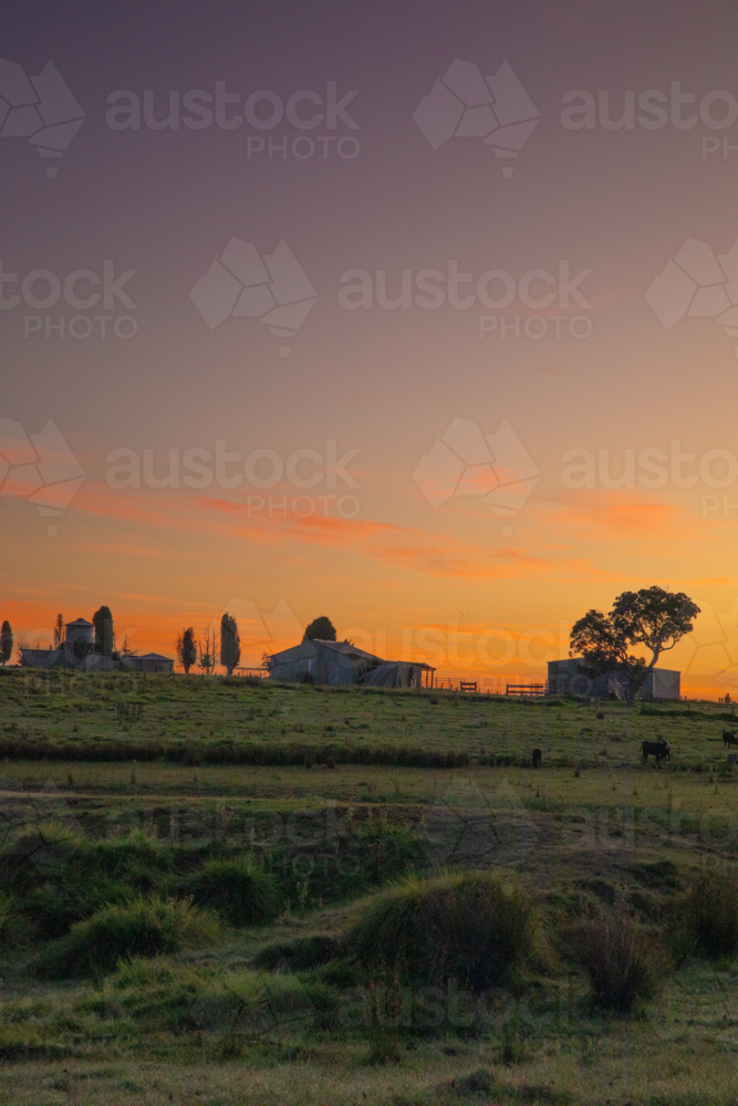 Silhouette of farmyard buildings under a sunrise sky - Australian Stock Image