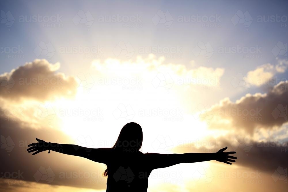 Silhouette of girl with arms outstretched - Australian Stock Image