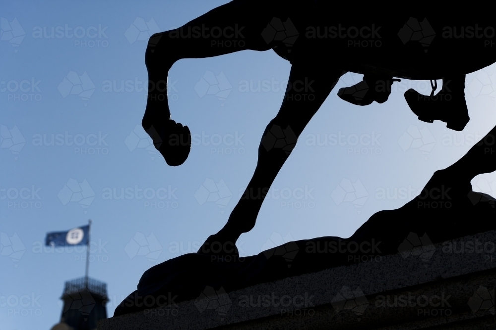 Silhouette of horse and rider statue with flag in background - Australian Stock Image