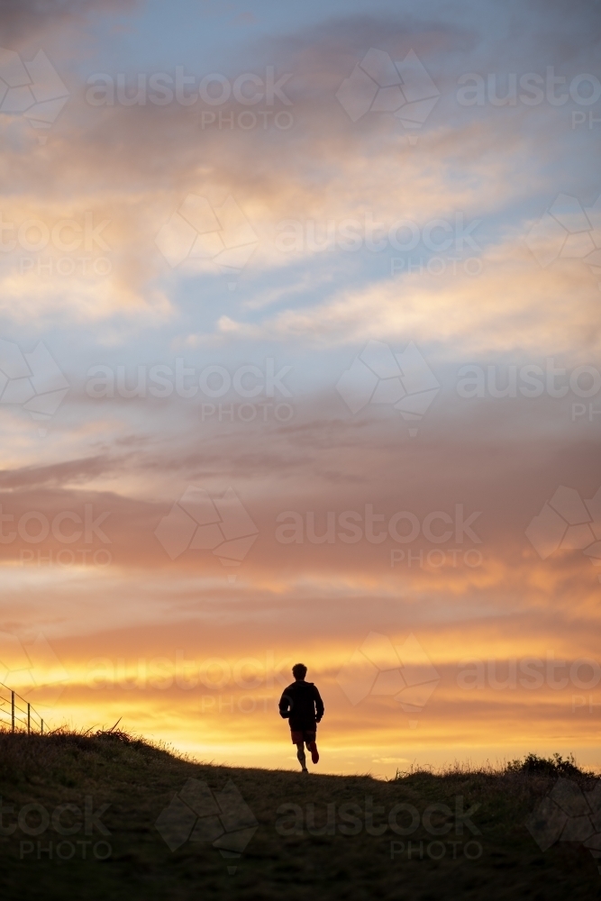 Silhouette of Man in Distance Running at Sunrise - Australian Stock Image