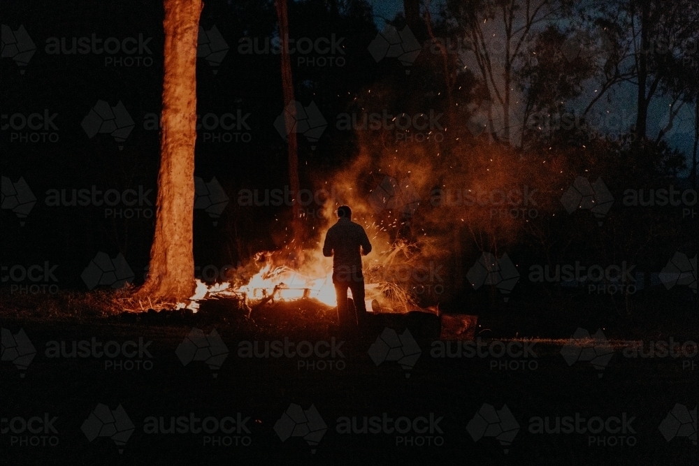 Silhouette of man standing at fire - Australian Stock Image