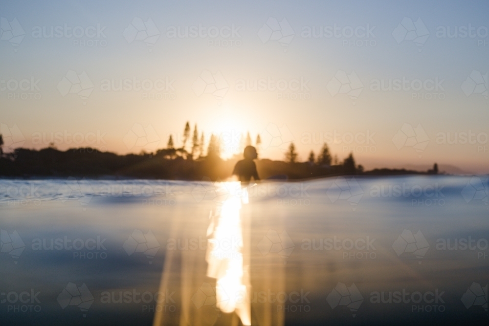 Silhouette of man surfing at sunset - Australian Stock Image